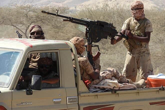 Yemeni fighters loyal to the government backed by the Saudi-led coalition fighting in the country ride in the back of a pickup truck with mounted heavy machine gun while closing in on a suspected location of an Al-Qaeda in the Arabian Peninsula (AQAP) leader during their the offensive in the Mesini Valley in the vast province of Hadramawt on February 21, 2018. Photo by Saleh Al-Obeidi/AFP via Getty Images.
