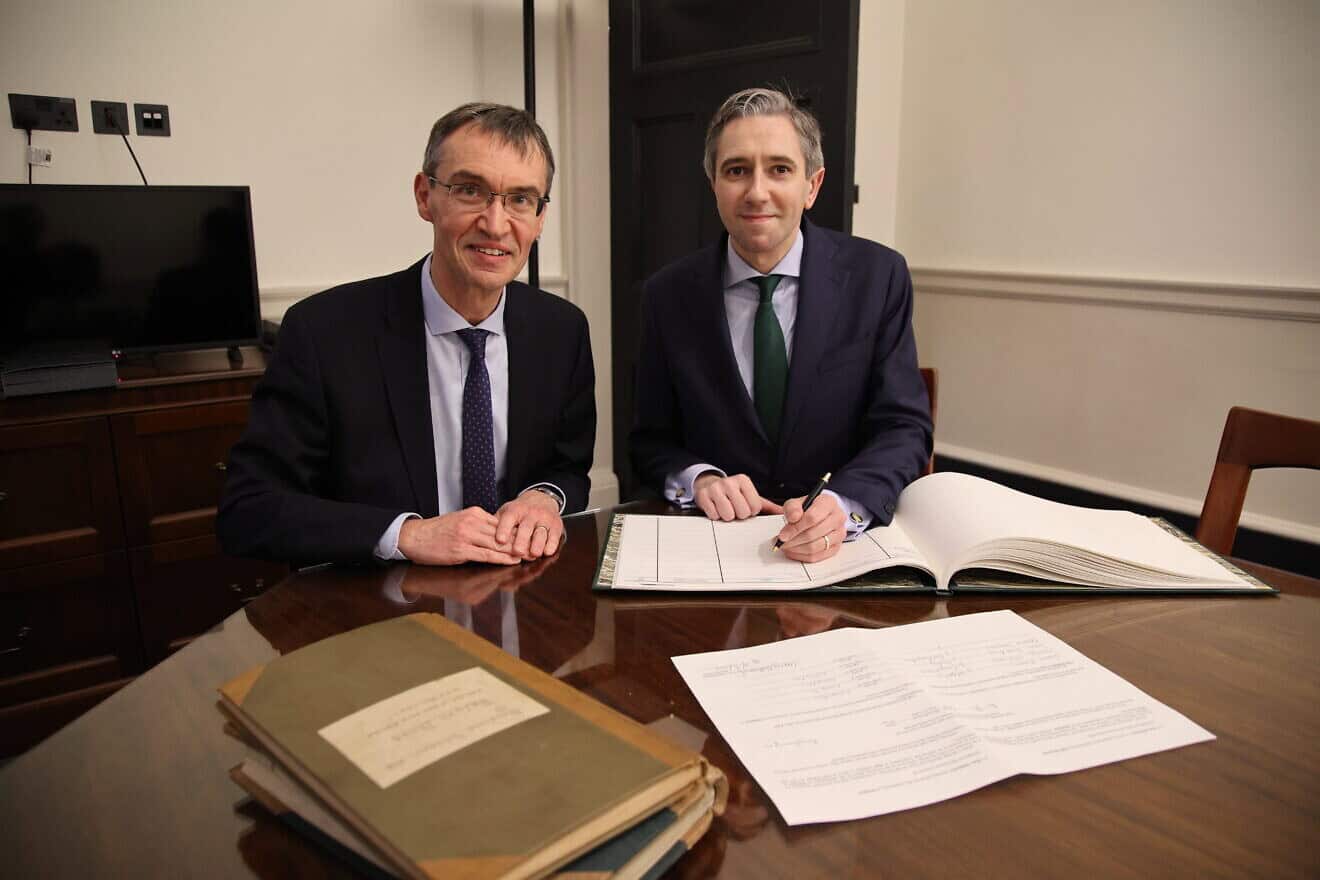 Simon Harris (right) signs a document in Dublin certifying him as Ireland's deputy prime minister, Dec. 4, 2024. Credit: Houses of the Oireachtas.