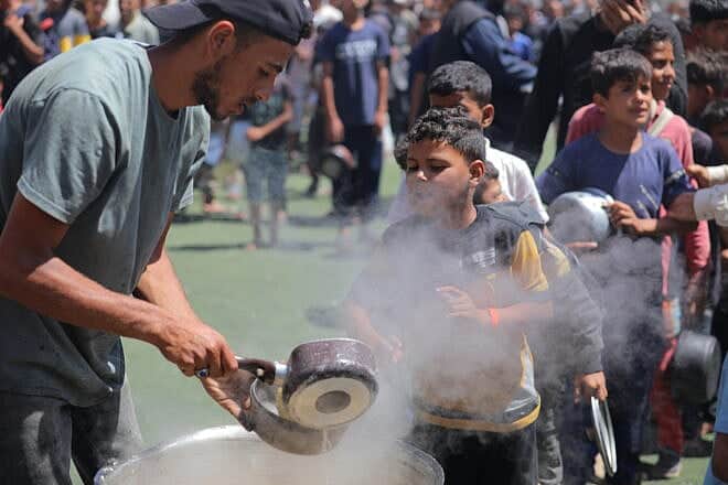 Palestinian children receive meals from volunteers in Gaza City, on May 29, 2025. Photo by Ali Hassan/Flash90.