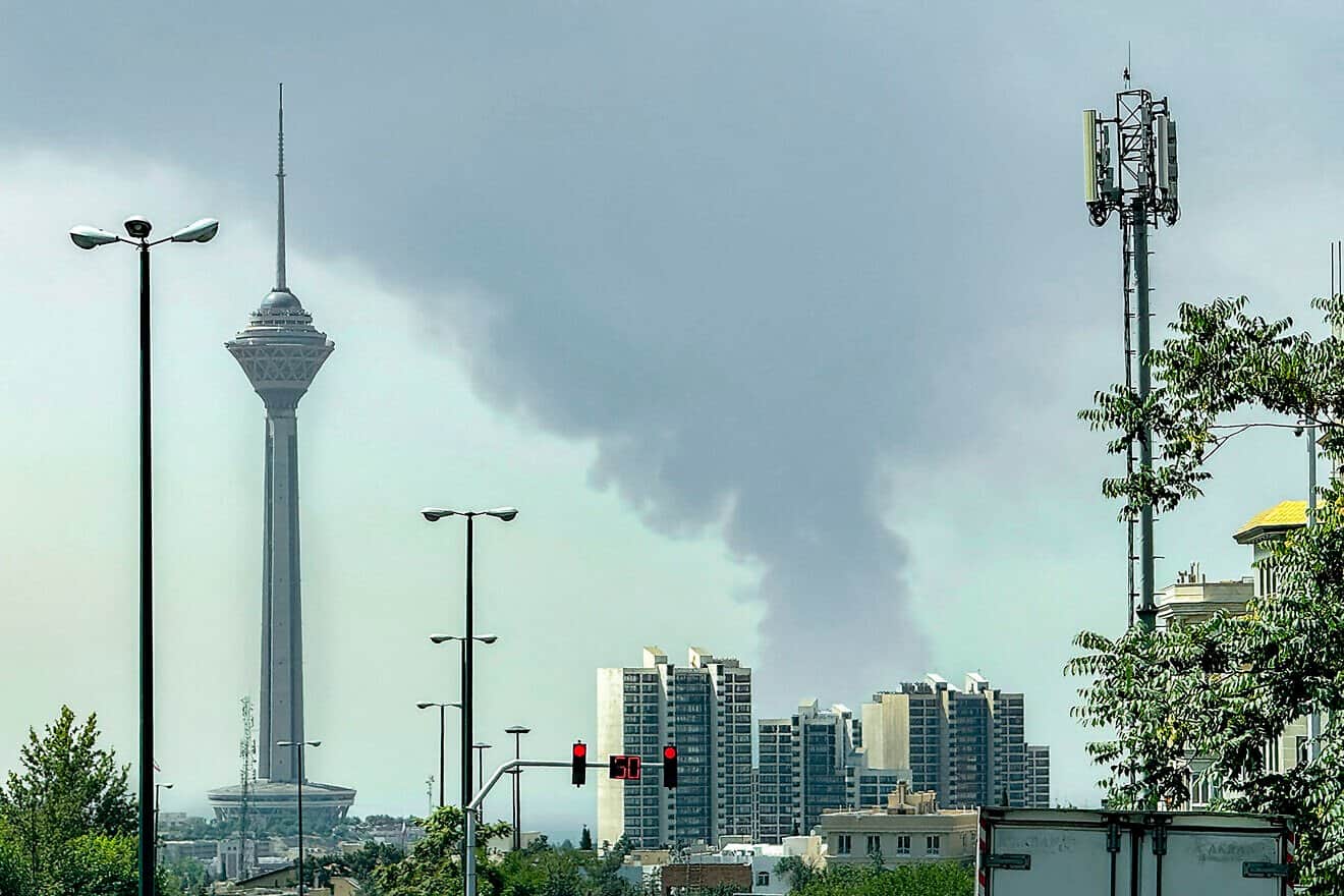 Smoke rises as Tehran's oil storage facility, targeted by Israel, burns in the background of the Milad Tower on June 15, 2025. Photo by Jonah/Middle East Images/AFP via Getty Images.