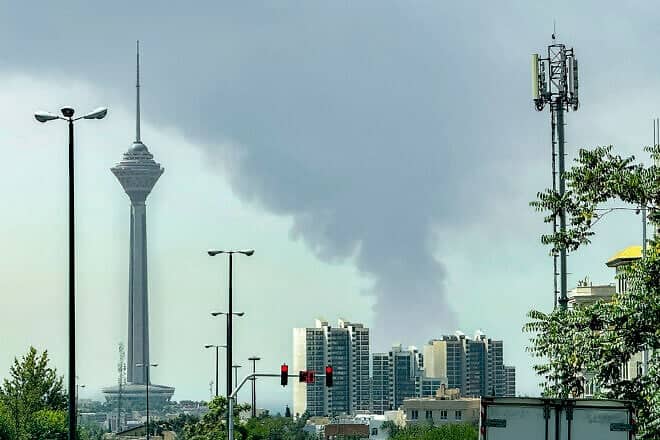 Smoke rises as Tehran's oil storage facility, targeted by Israel, burns in the background of the Milad Tower on June 15, 2025. Photo by Jonah/Middle East Images/AFP via Getty Images.
