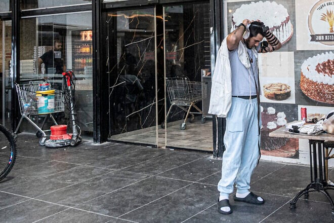 Ouriel Hattab puts on tefillin outside a bakery in Kiryat Yam, Israel, on June 15, 2025. Photo by Canaan Lidor.