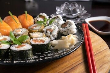 Assorted sushi rolls and sashimi on a plate with chopsticks. Credit: Diego Pontes/Pexels.
