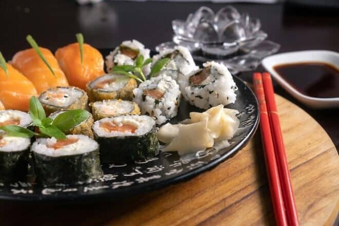 Assorted sushi rolls and sashimi on a plate with chopsticks. Credit: Diego Pontes/Pexels.