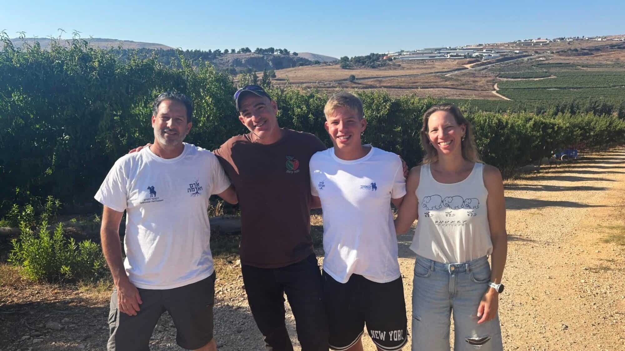 From left: Yizhar Barak, the principal of the new agricultural school at Kibbutz Yiron, with the Asaf, Ma’ayan and Yitav Schwartz on the fields overlooking the border with Lebanon, July 2025. Photo by Natalie Gattegno.