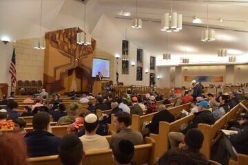 On the bimah, Dan Rosen, co-founder and co-chair of the new Emissary app, addresses a synagogue audience on how to best use it. Credit: Courtesy.