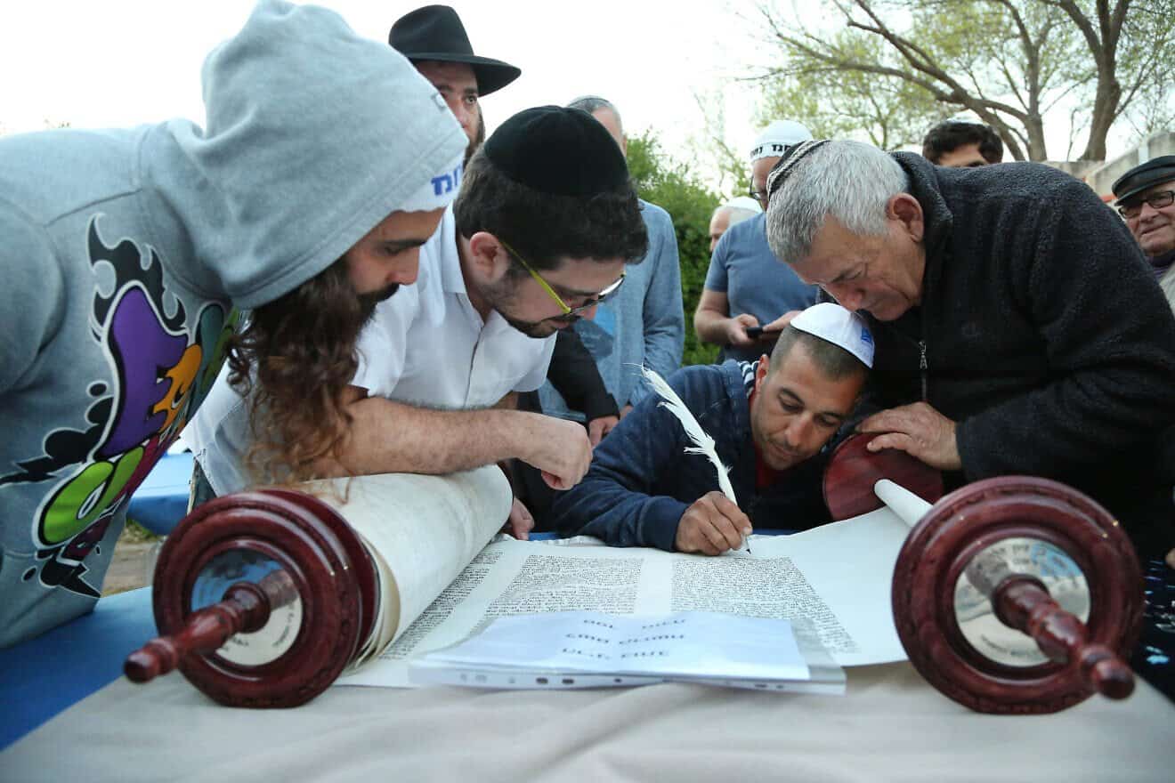 A few people are honored with writing the last letters of a new Torah scroll for a synagogue in Haniel, Israel, on Oct. 19, 2016. Photo by Chen Leopold/Flash90.