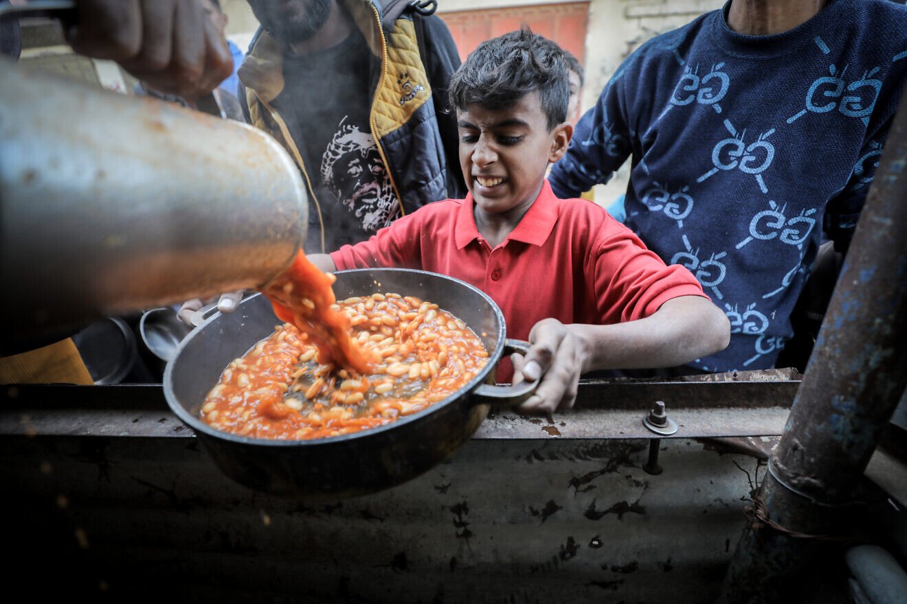 Palestinians receive meals distributed by charities in Khan Yunis in the southern Gaza Strip, Dec. 22, 2024. Photo by Ali Hassan/Flash90.