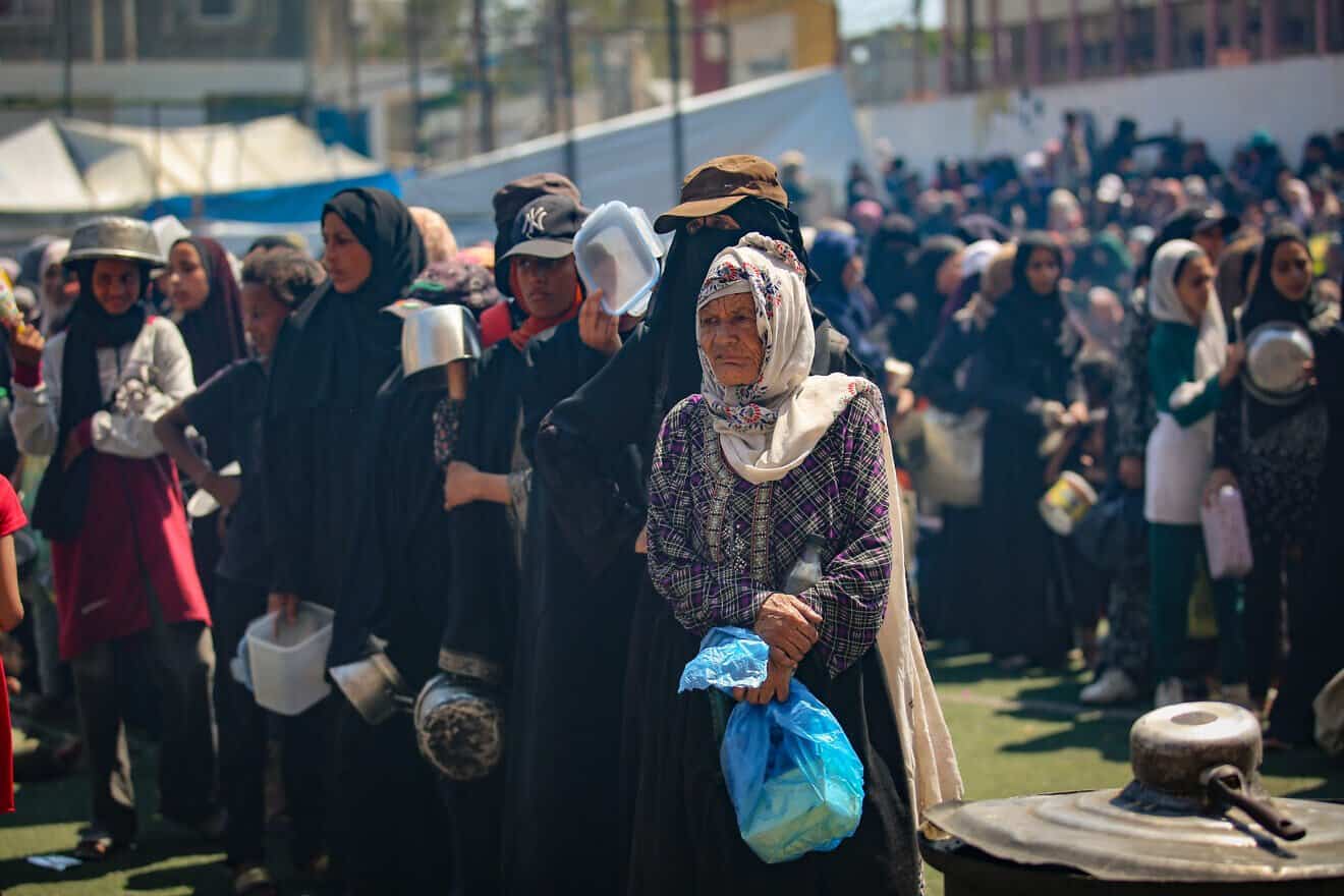 Palestinians receive meals from volunteers in Gaza City on July 25, 2025. Photo by Ali Hassan/Flash90.