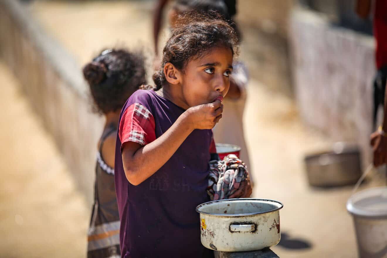 A Palestinian child eats food given out by volunteers in Gaza City, on July 25, 2025. Photo by Ali Hassan/Flash90.