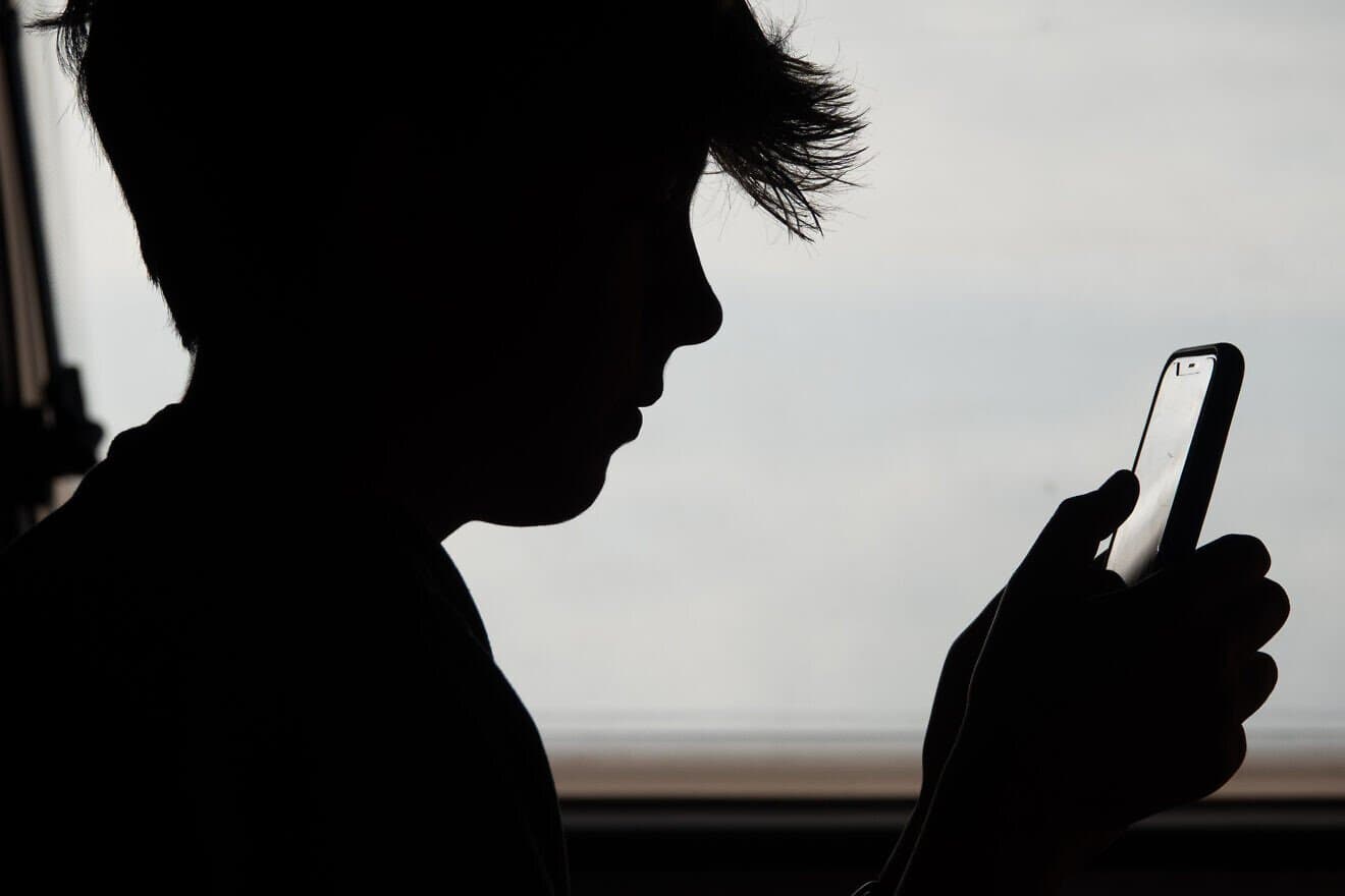 In this illustrative photo, a 13-year-old boy looks at an iPhone screen in Penzance, England, on May 26, 2025. Photo by Matt Cardy/Getty Images.