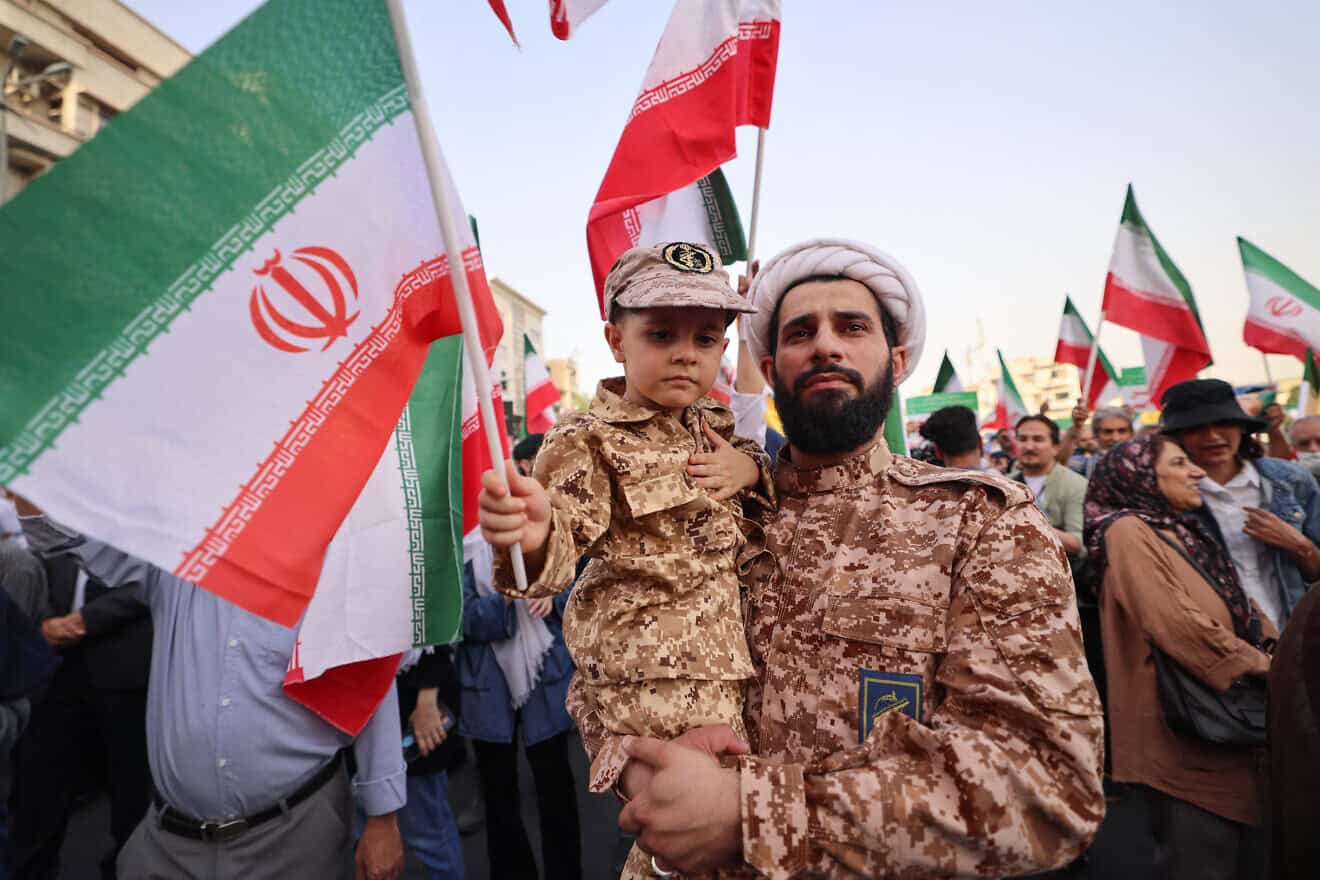 An Iranian cleric and his son, dressed in military fatigues, take part in celebrations following a ceasefire between Iran and Israel at Enghlab Square in the capital of Tehran, June 24, 2025. Photo by Atta Kenare/AFP via Getty Images.
