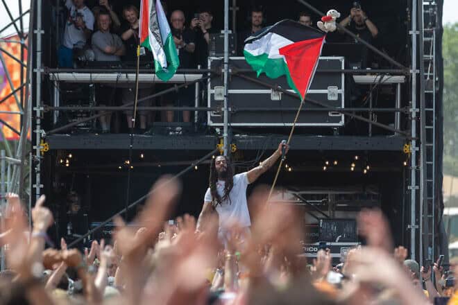 Bob Vylan waves a Palestinian flag as he performs on the West Holts stage on day four of Glastonbury Festival 2025 at Worthy Farm, Pilton in Glastonbury, England, on June 28, 2025. Avon and Somerset Police have announced a criminal investigation into the performances of Bob Vylan and the Irish-language rap band Kneecap, known for making pro-Palestinian comments during their live performances. Photo by Matt Cardy/Getty Images.