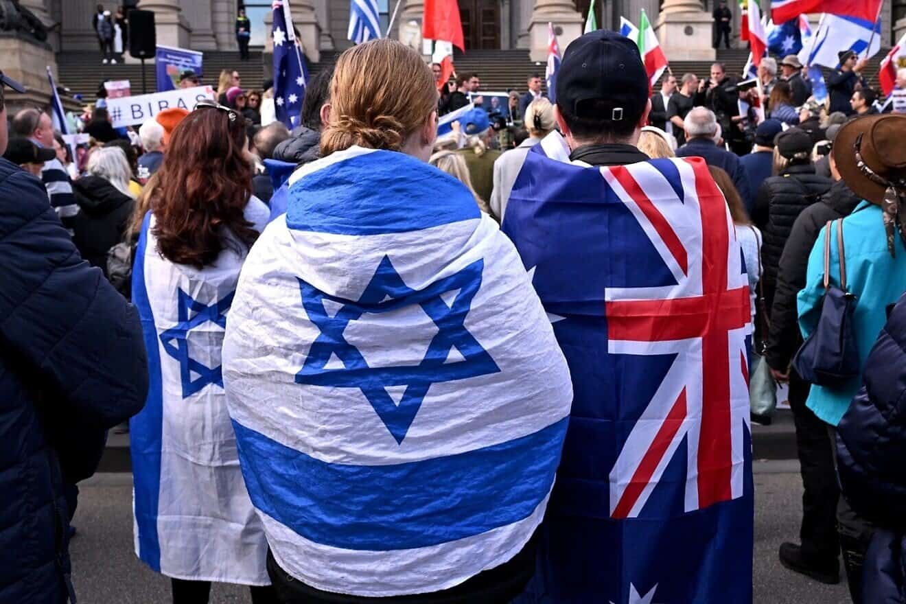 People wearing flags of Israel and Australia listen to speeches at a rally in Melbourne on July 6, 2025, after the front door of a synagogue was set ablaze on July 4. Photo by William West/AFP via Getty Images.