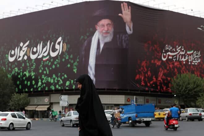 An Iranian crosses a street next to a billboard bearing the portrait of Iranian Supreme Leader Ayatollah Ali Khamenei at Enqelab Square in Tehran, July, 9, 2025. Photo by AFP via Getty Images.