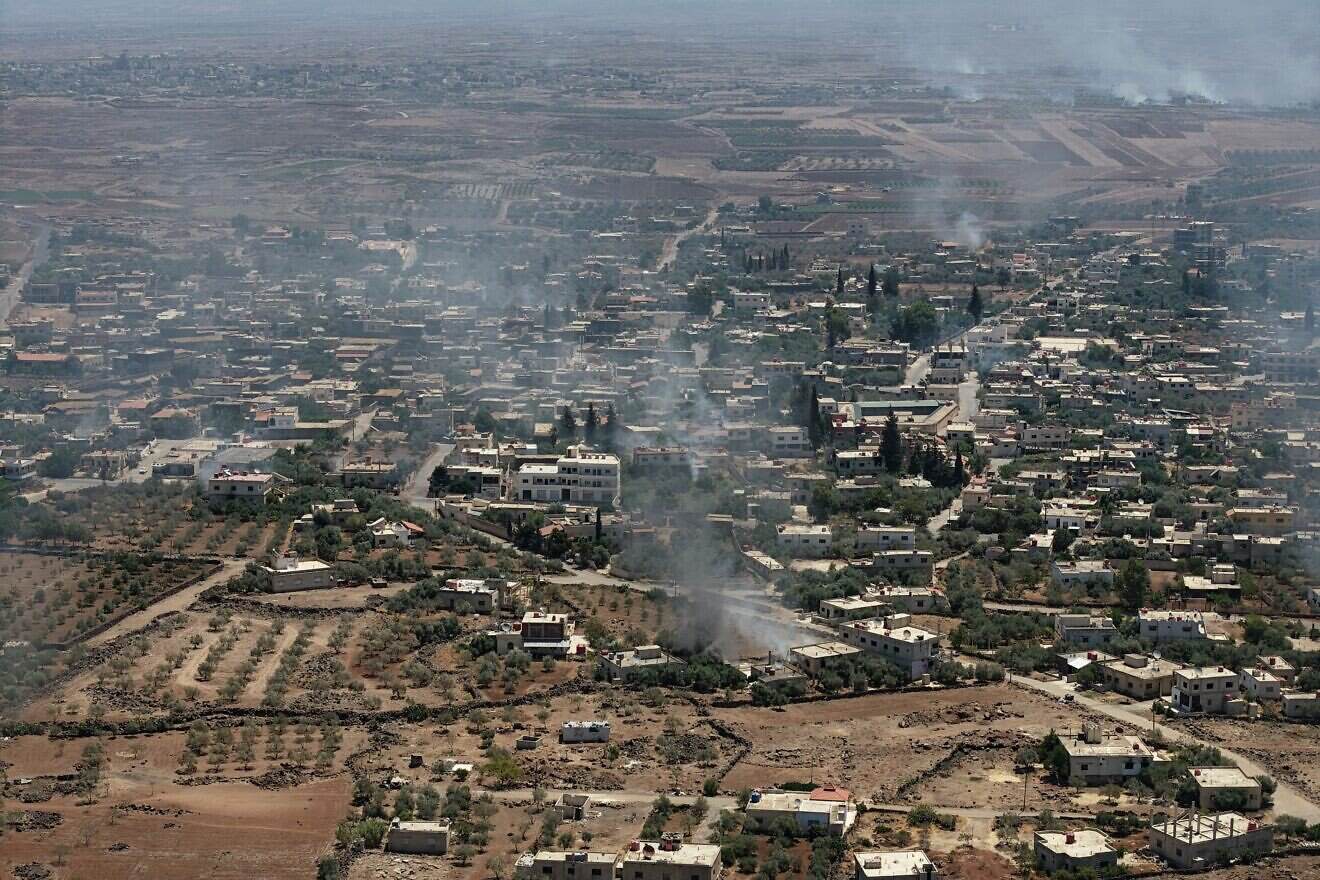 This aerial photograph shows smoke rising above buildings in al-Mazraa village in Syria's southern Sweida governorate as clashes between fighters from Bedouin tribes and Druze gunmen continues  on July 07, 2025 in Sweida, Syria. Photo by Ali Haj Suleiman/Getty Images.