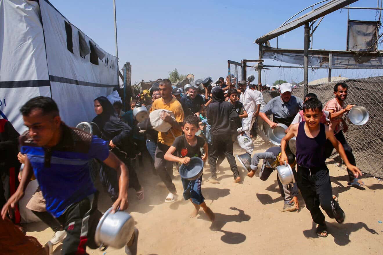Palestinians rush to queue in line at a charity kitchen in the Mawasi area of Khan Yunis in the southern Gaza Strip, on July 22, 2025. Photo by AFP via Getty Images.