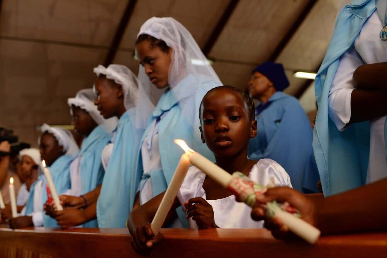 A girl lights a candle during a mass commemorating late South African former president Nelson Mandela in Soweto, near Johannesburg, on Dec. 8, 2013. Photo by Pedro Ugarte/AFP via Getty Images.