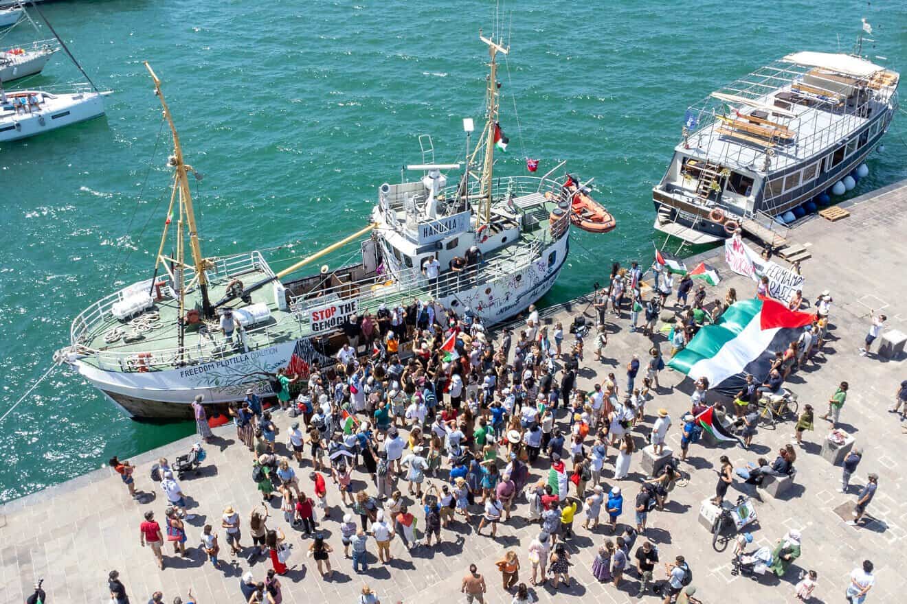People gather around the "Handala" at a port in Syracuse, Sicily, ahead of the vessel's departure to run the Gaza blockade, July 13, 2025. Photo by Giovanni Isolino/AFP via Getty Images.
