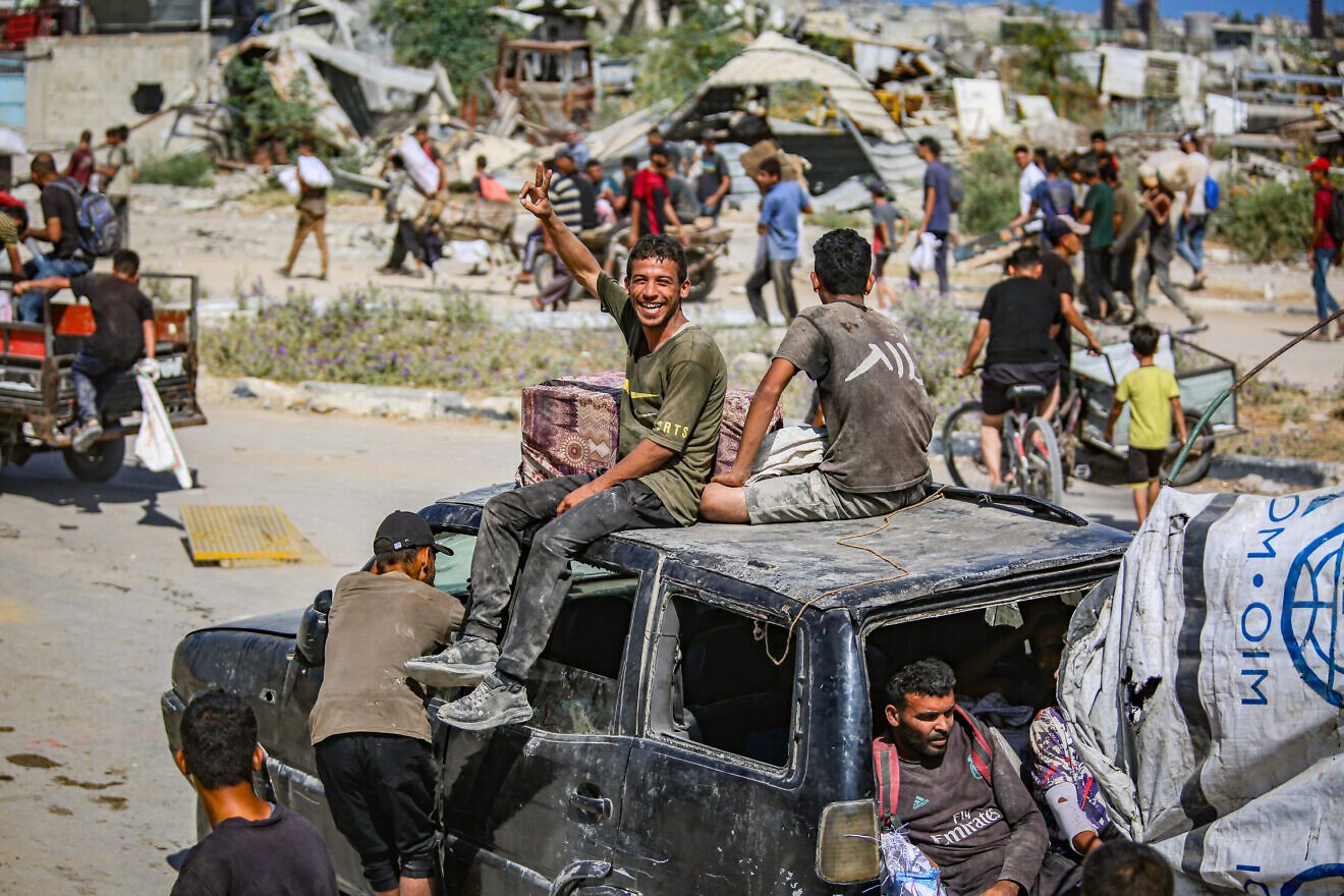 Displaced Palestinians carry food parcels and supplies from a GHF aid distribution point at the “Netzarim corridor” in central Gaza, July 31, 2025. Photo by Ali Hassan/Flash90.