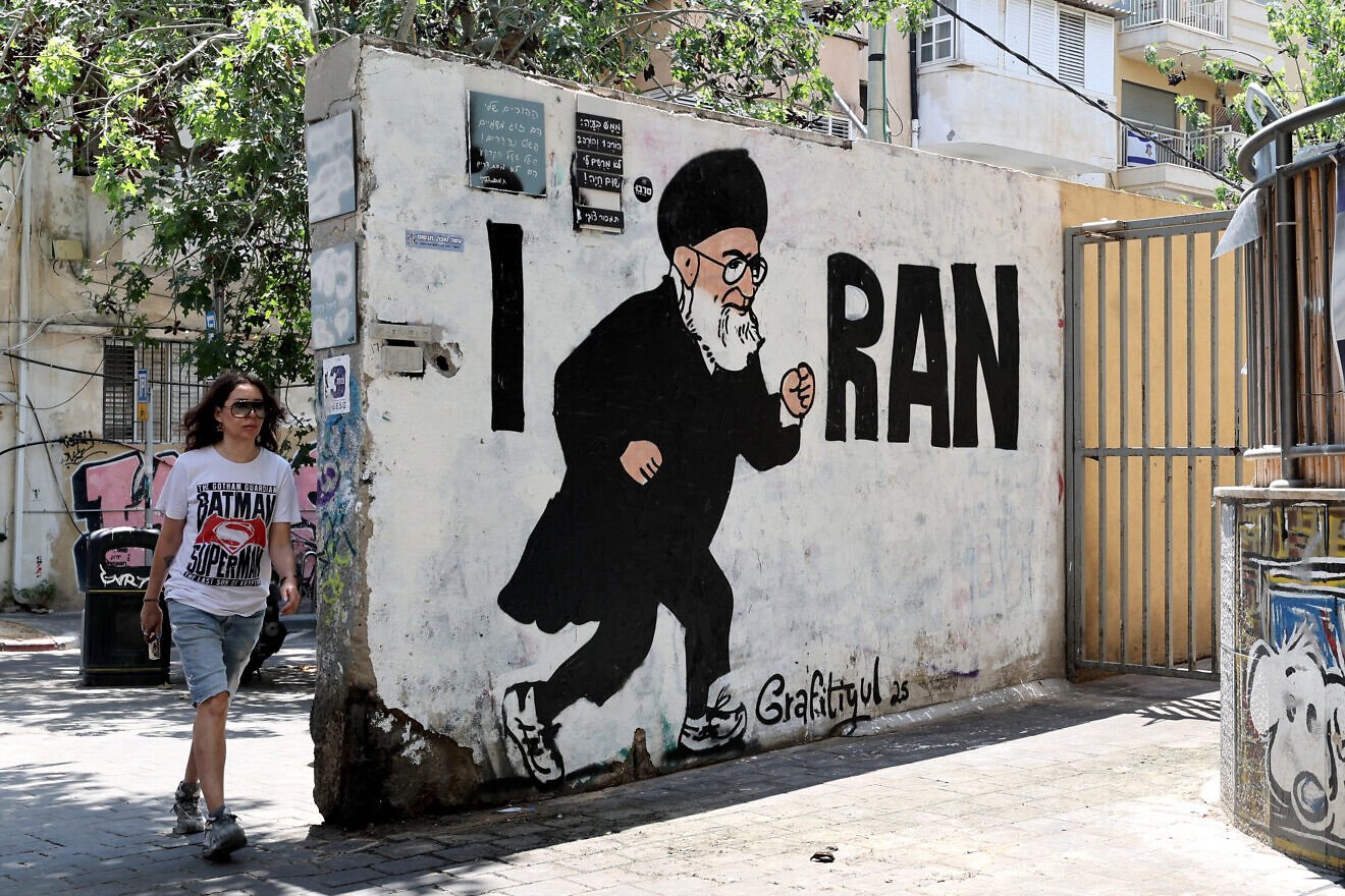 People walk past a mural drawn by the “Grafitiyul” graffiti art group depicting Iran's Supreme Leader Ayatollah Ali Khamenei, on a street in the Israeli coastal city of Tel Aviv, on July 22, 2025. Photo by JACK GUEZ/AFP via Getty Images.