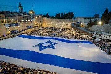 People hold a giant Israeli flag at the Western Wall in Jerusalem Old City on the eve of Jerusalem Day, May 25, 2025. Photo by Chaim Goldberg/Flash90.