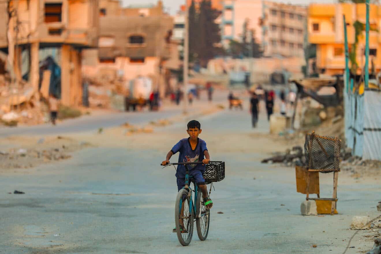 A Palestinian boy rides his bike at sunset in Al-Bureij refugee camp in the central Gaza Strip, July 22, 2025. Photo by Ali Hassan/Flash90.