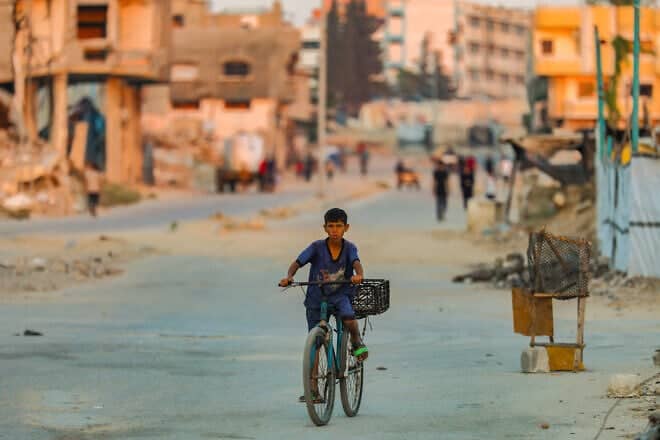 A Palestinian boy rides his bike at sunset in Al-Bureij refugee camp in the central Gaza Strip, July 22, 2025. Photo by Ali Hassan/Flash90.