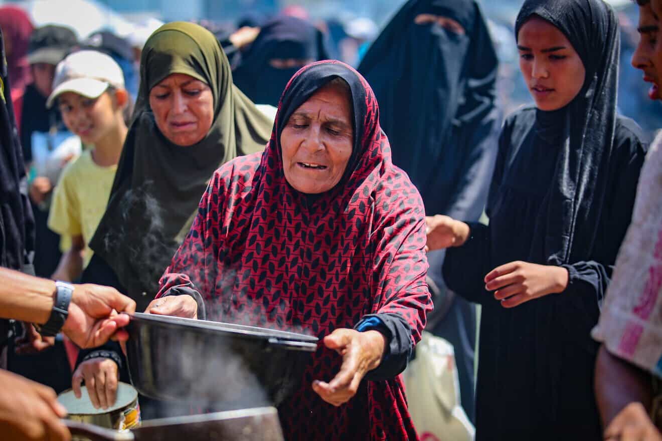 Palestinians receive meals from volunteers in Gaza City, on July 25, 2025. Photo by Ali Hassan/Flash90.