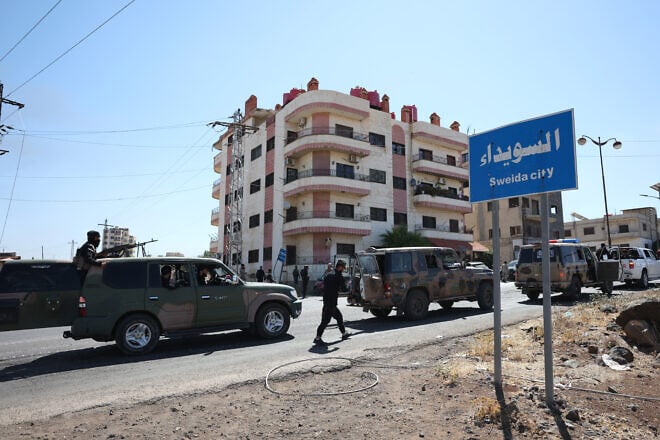A convoy of Syrian military and security forces passes a sign for Sweida city in Syria, on July 15, 2025. Photo by Stringer/Getty Images.