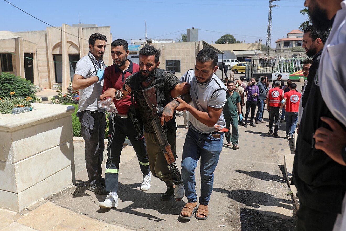A Bedouin tribal gunman is helped to a hospital in Izra, in Syria's southern Daraa Province, after being wounded in combat against Druze fighters in nearby Sweida on July 19, 2025. Photo by Abdulaziz Ketaz/AFP via Getty Images.