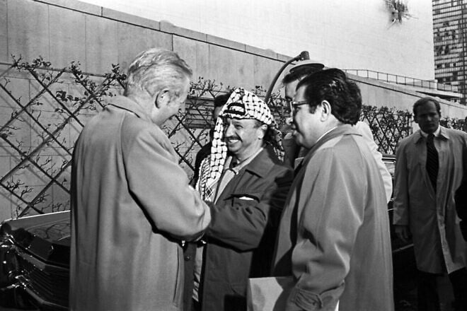 PLO leader Yasser Arafat, shakes hands with H.A. Trimble, chief of the U.N. Security and Safety Section, upon his arrival at United Nations Headquarters with PLO member Sadat Hassan at his right on Nov. 13, 1974. Credit: U.N. Photo/Michos Tzovaras.