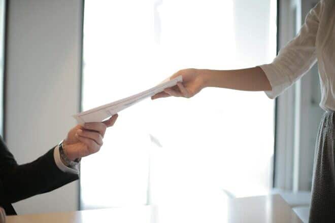 Employee handing paperwork across a desk. Credit: Andrea Piacquadio/Pexels.