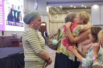A woman embraces Iris Haim, the mother of Yotam Haim, 28, a hostage in Gaza who was mistakenly killed by IDF forces after escaping Hamas captivity, at the end of the OneFamily symposium on July 30, 2025. Photo by Sharon Altshul.