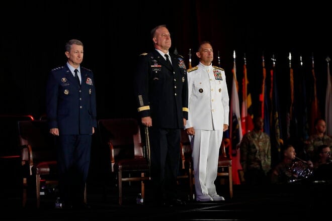 U.S. Army Gen. Michael Erik Kurilla (center), the outgoing commander of U.S. Central Command (CENTCOM), with U.S. Air Force Gen. Dan Caine (left), chairman of the Joint Chiefs of Staff, and U.S. Navy Adm. Brad Cooper (right), the incoming commander of CENTCOM, stand at attention at a change of command ceremony in Tampa, Fla., on Aug. 8, 2025. Credit: Tom Gagnier/U.S. Central Command Public Affairs.