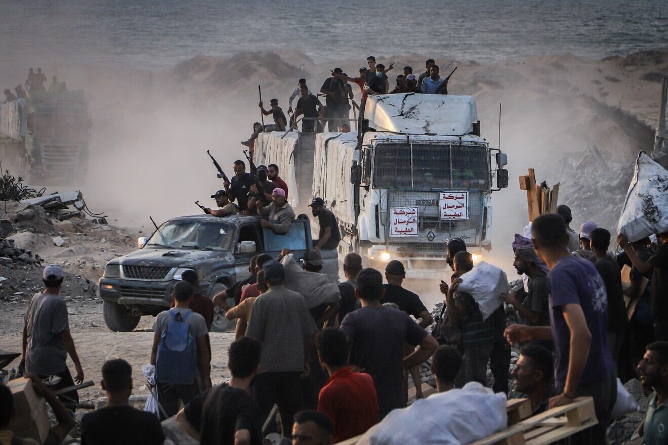 Armed Palestinians sit on trucks carrying humanitarian aid near the Zikim border crossing between Israel and Beit Lahia in the northern Gaza Strip, Aug. 18, 2025. Photo by Khalil Kahlout/Flash90. Armed Palestinians sit on trucks carrying humanitarian aid near the Zikim border crossing between Israel and Beit Lahia in the northern Gaza Strip, Aug. 18, 2025. Photo by Khalil Kahlout/Flash90.