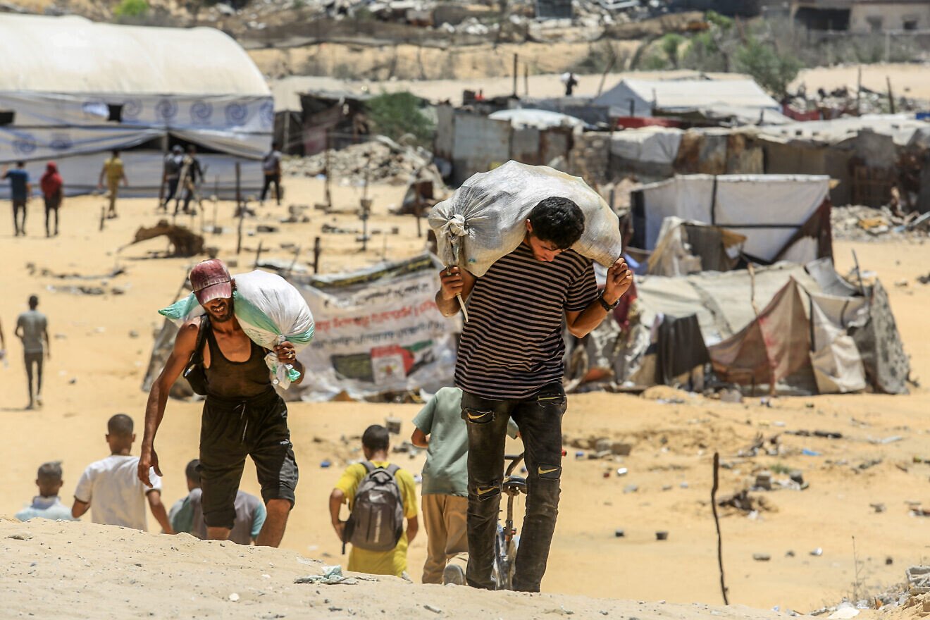Palestinians carry humanitarian aid in Rafah, in the southern Gaza Strip, July 31, 2025. Photo by Abed Rahim Khatib/Flash90.
