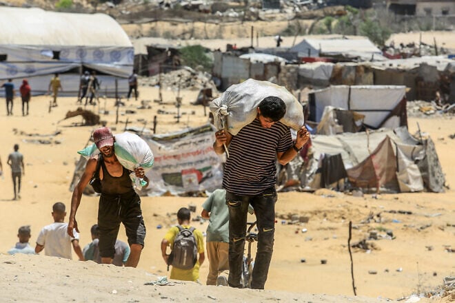 Palestinians carry humanitarian aid in Rafah, in the southern Gaza Strip, July 31, 2025. Photo by Abed Rahim Khatib/Flash90.