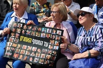 (From left): Holocaust survivors Dvora Weinstein, Irene Shashar and Aliza Hershkovich holding a sign calling for the release of the hostages ahead of the March of the Living in Auschwitz, April 2025. Photo by Yossi Zeliger.
