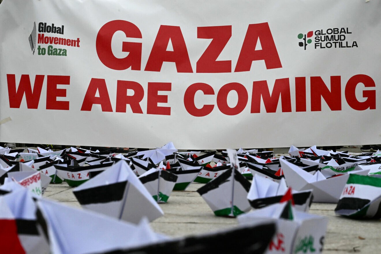 A flotilla of paper boats are laid on the ground near a banner reading "Gaza We are Coming" during a demonstration in support of Gaza and Palestinian people at Venice Lido during the 82nd Venice International Film Festival, on August 30, 2025. Photo by Stefano Rellandini/AFP via Getty Images.
