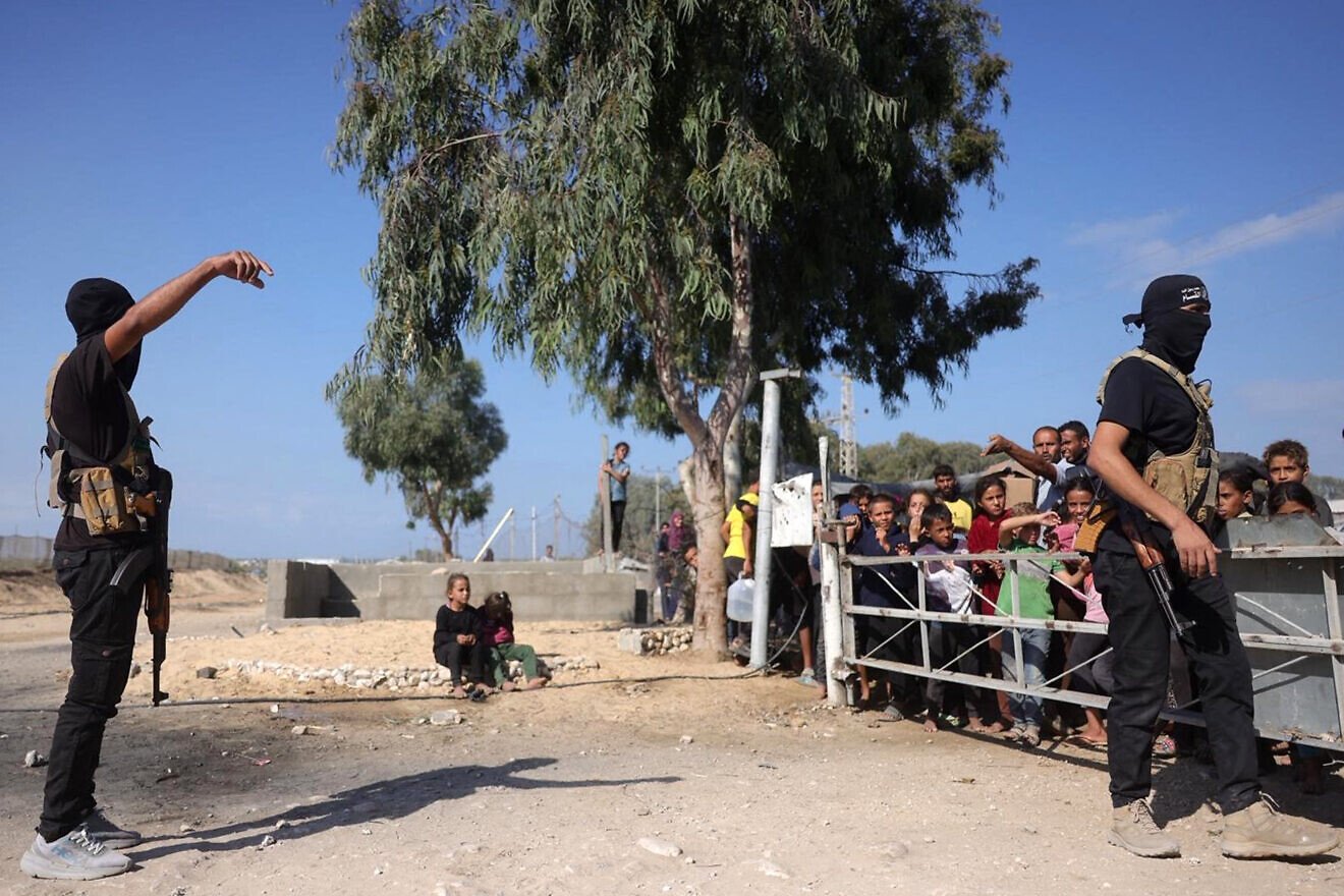 Hamas terrorists stand await the arrival of vehicles of the International Committee of the Red Cross in the south of Deir el-Balah, the central Gaza Strip, before handing over the second batch of hostages to be released, on Oct. 13, 2025. Photo by Bashar Taleb via Getty Images.