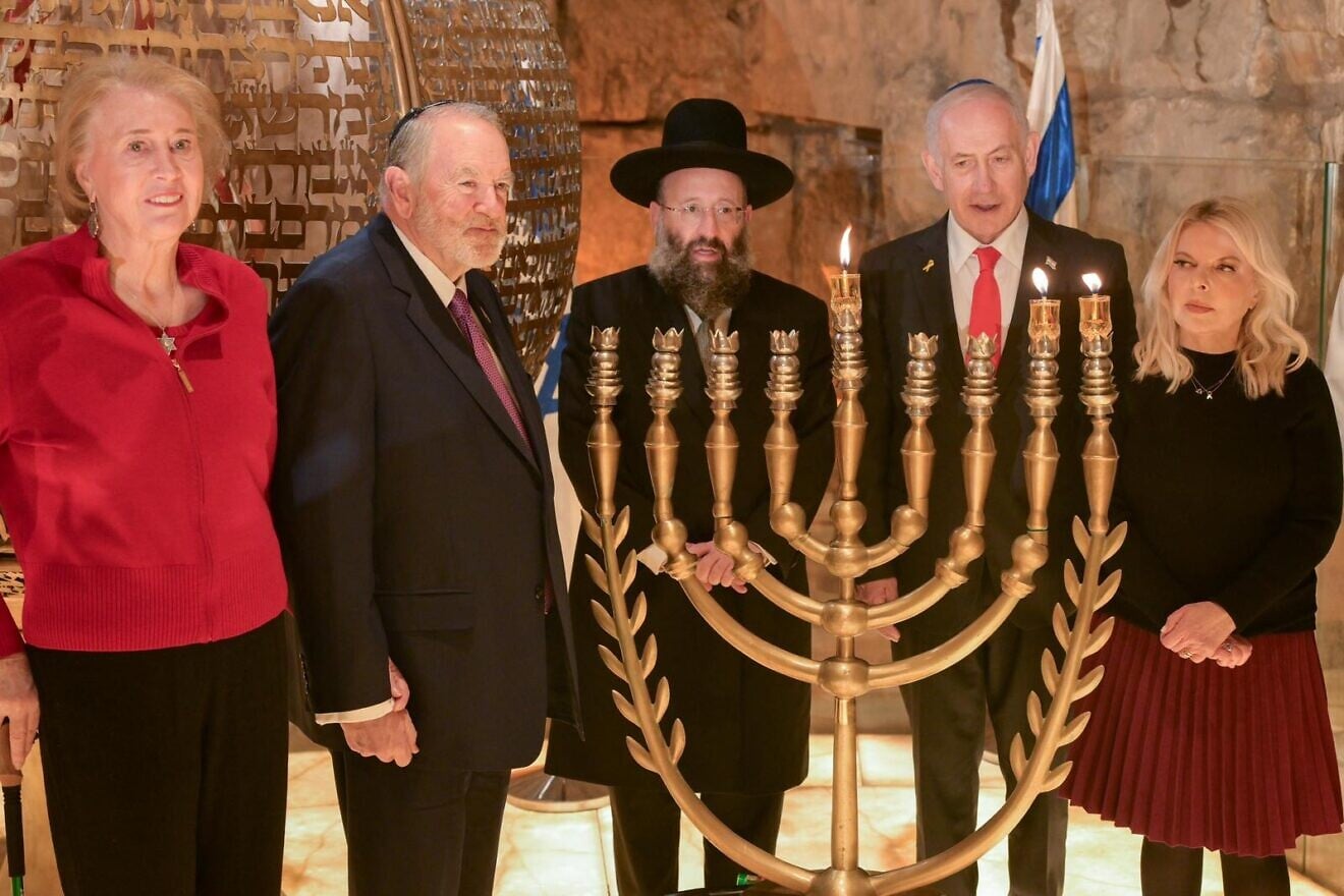 Le Premier ministre israélien Benjamin Netanyahu et son épouse, Sara, allument la deuxième bougie de Hanoukka au Mur occidental à Jérusalem avec le rabbin Shmuel Rabinowitz et l'ambassadeur américain Mike Huckabee et son épouse, Janet, le 15 décembre 2025. Crédit : Ma'ayan Toaf/ GPO.