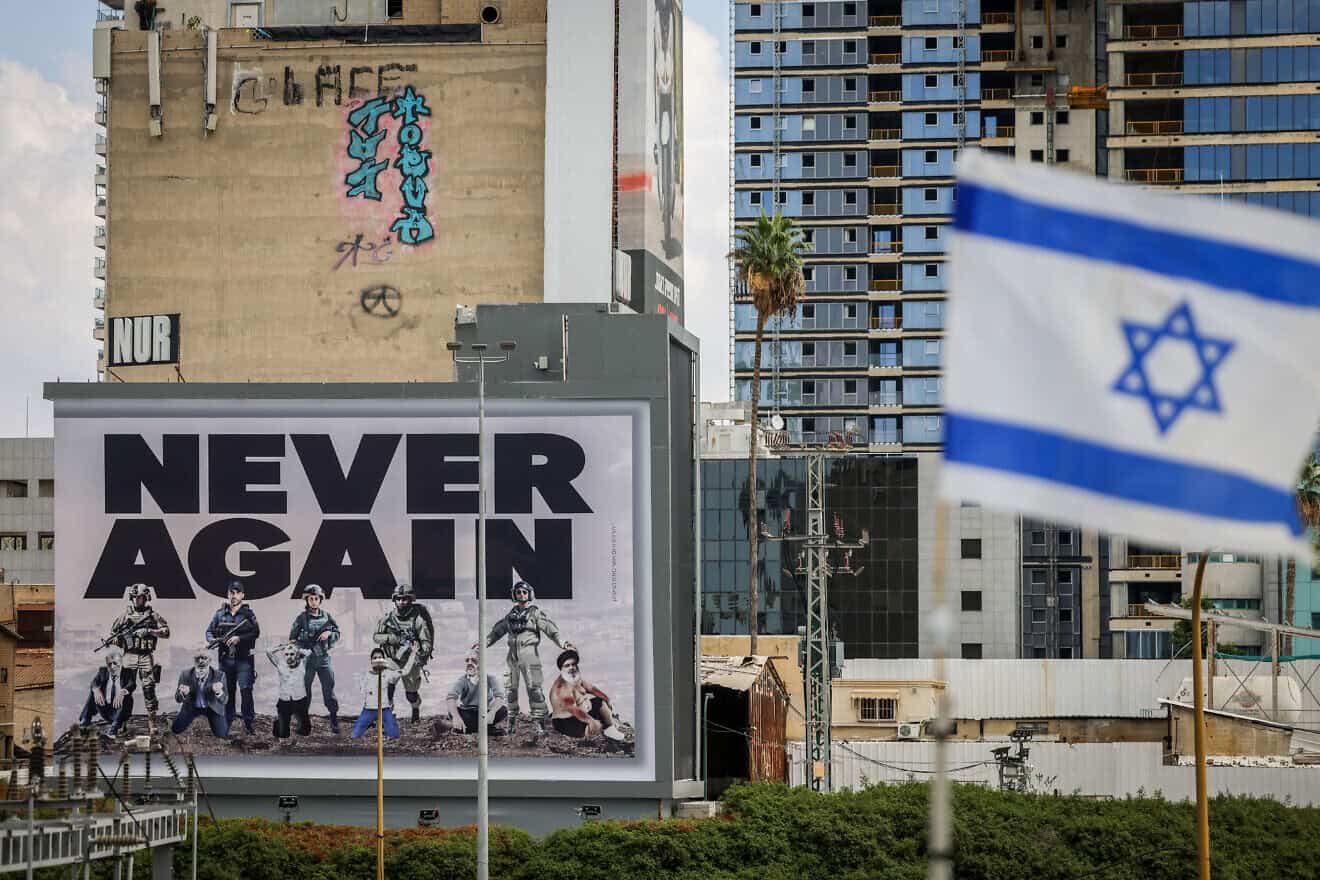 A large billboard with the words "Never Again" is seen above the Ayalon highway in Tel Aviv, Oct. 18, 2023. Photo by Chaim Goldberg/Flash90. A large billboard with the words "Never Again" is seen above the Ayalon highway in Tel Aviv, Oct. 18, 2023. Photo by Chaim Goldberg/Flash90.