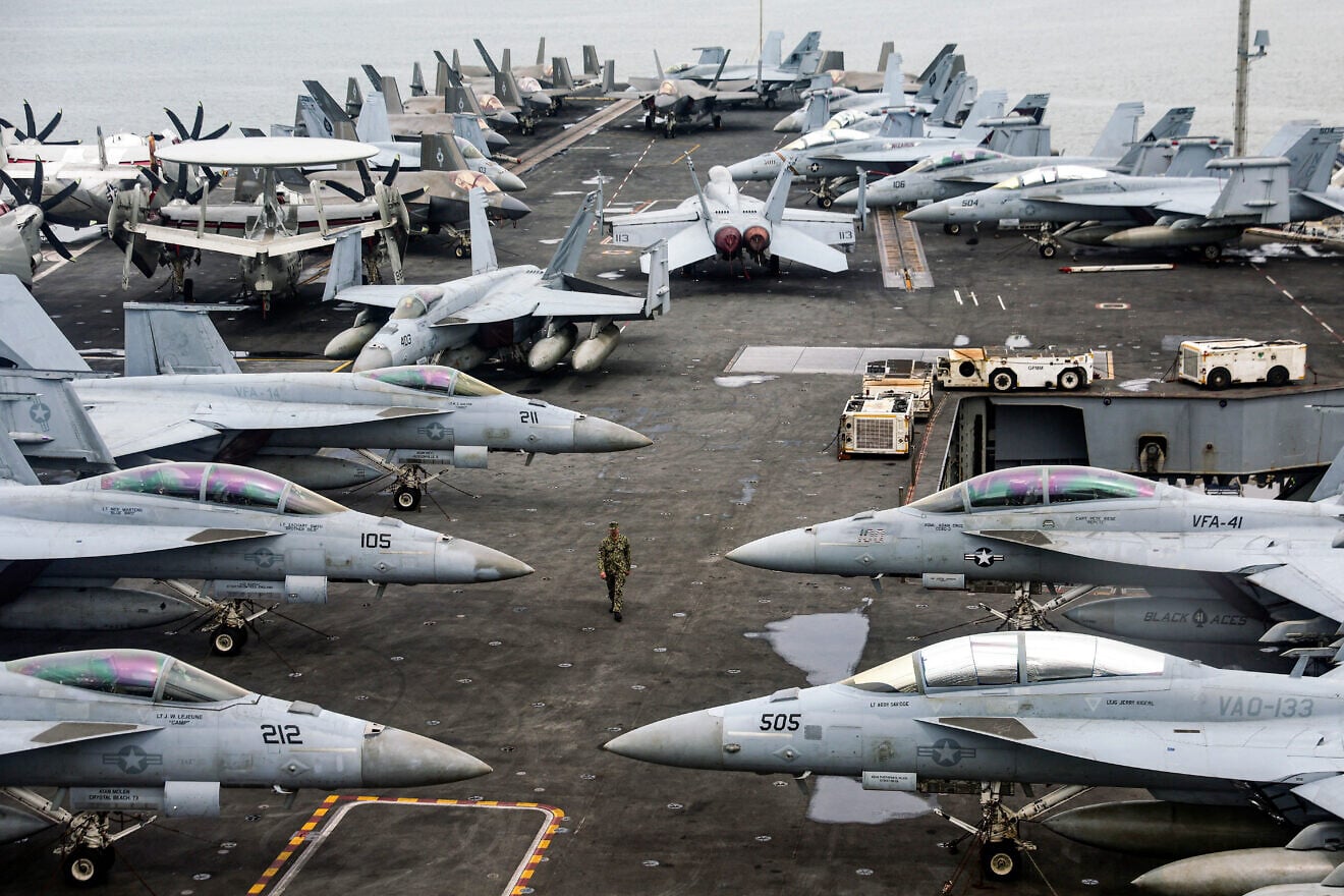 A U.S. Navy officer walks past F-18 fighter jets parked on the flight deck of the Nimitz-class aircraft carrier USS “Abraham Lincoln” during a media tour in Port Klang, on the outskirts of Kuala Lumpur, Malaysia, on Nov. 26, 2024. Photo by Fazry Ismail/POOL/AFP via Getty Images.